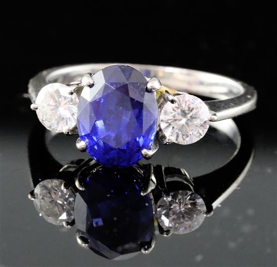 An 18ct white gold, synthetic? sapphire and diamond three-stone ring, size N.